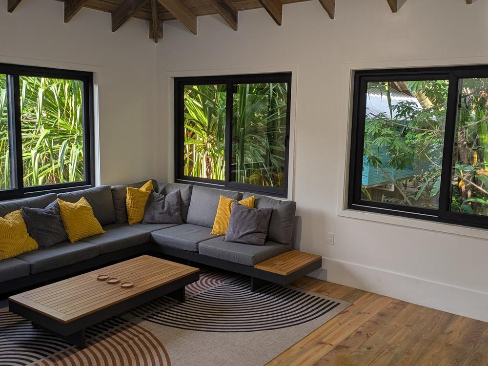 Salon avec grand sectionnel et fenêtres sur la jungle